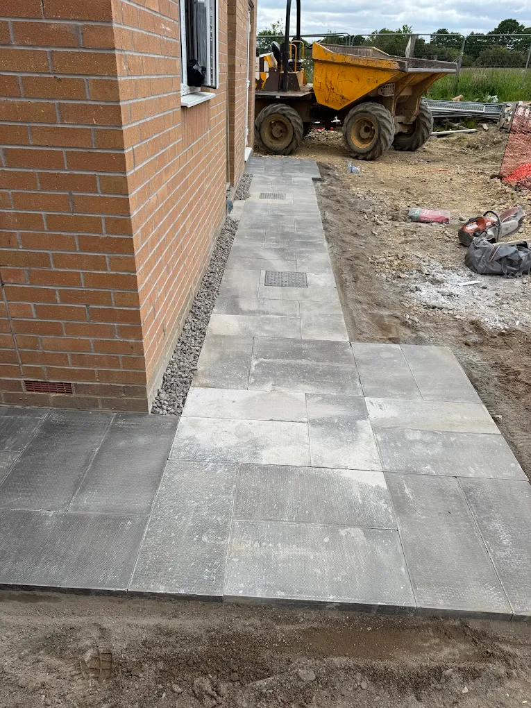 Grey paving pathway wrapping around a new-build property